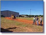 The Claiborne Parish Police Jury Road Crew is assisting Homer Mayor Huey Dean and the Town of Homer by providing labor and equipment to build an entry road to the north side of the building occupied by Stallion, Inc. at the Homer Airport. A new door will also be installed on that side of the building. Stallion presently employs 30-35 persons with plans to expand and hire an additional 40 employees. To meet requirements of FAA at the Airport, the north exit was needed to keep the trucks off the runway and apron. Last week, Police Jury employees Jim Morgan, Larry Crew, Joe P. Fielding, and Jimmy White (not pictured) delivered and spread dirt for the roadway.